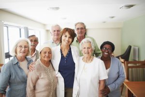 A smiling female doctor surrounded by a group of her elderly patients